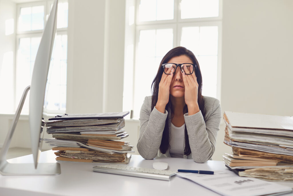 A lot of work in the office. Tired busy businesswoman is working with computer. Female worker covers his face with his hands while sitting at the workplace.